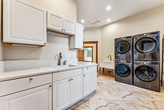 laundry area featuring cabinets, sink, stacked washing maching and dryer, and washing machine and clothes dryer