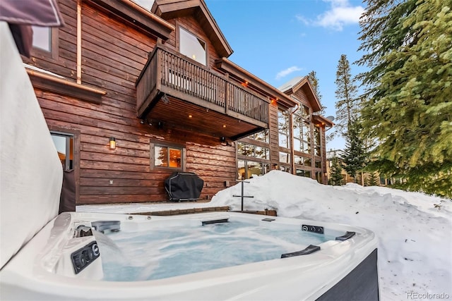 snow covered patio featuring a grill, a balcony, and a hot tub