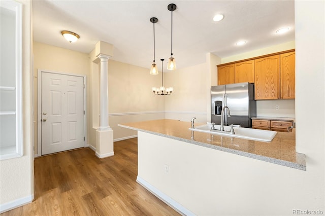 8427 S Hoyt Way Unit 203, Littleton, CO 80128 - kitchen with stainless steel fridge, a peninsula, light wood-style flooring, decorative light fixtures, and decorative columns