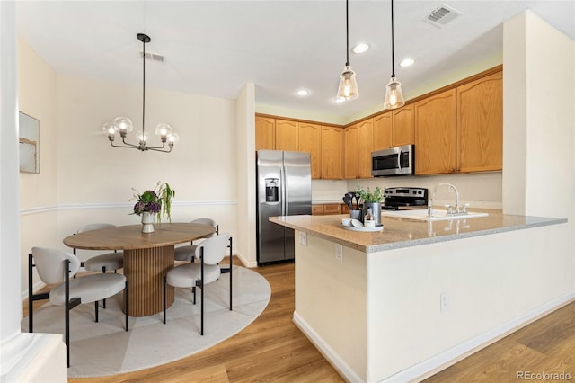 8427 S Hoyt Way Unit 203, Littleton, CO 80128 - kitchen with appliances with stainless steel finishes, light wood-style floors, recessed lighting, a peninsula, and decorative light fixtures