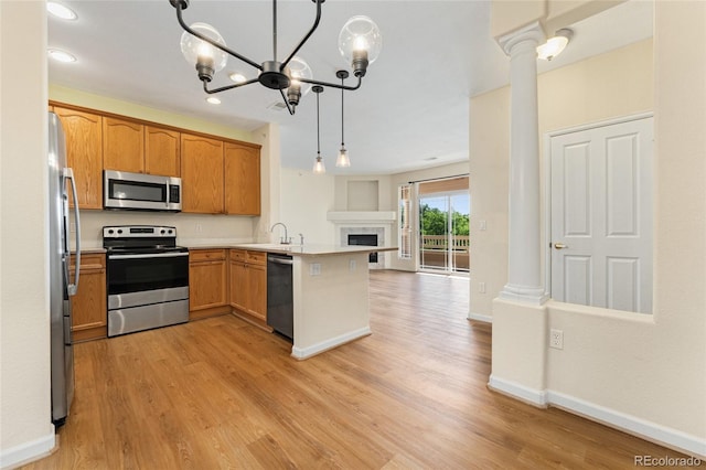 8427 S Hoyt Way Unit 203, Littleton, CO 80128 - kitchen featuring stainless steel appliances, open floor plan, a peninsula, light wood-style flooring, and a fireplace