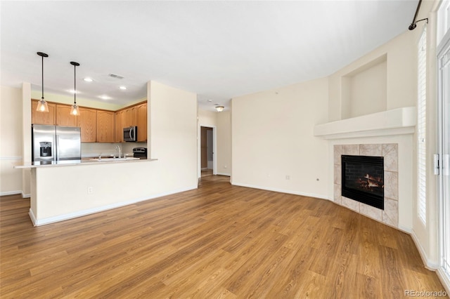8427 S Hoyt Way Unit 203, Littleton, CO 80128 - unfurnished living room featuring light wood-style flooring, a tiled fireplace, and recessed lighting