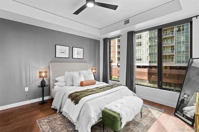 bedroom with ceiling fan, hardwood / wood-style floors, and a raised ceiling