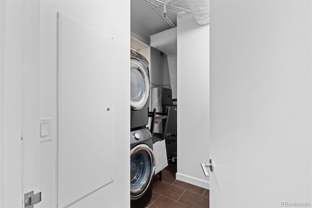 laundry room featuring stacked washer and clothes dryer and dark tile patterned floors