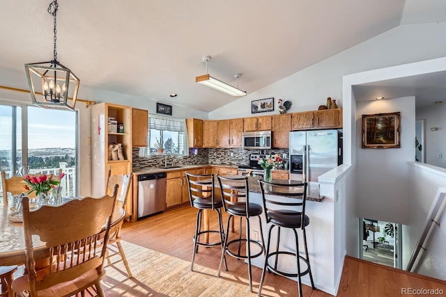 kitchen featuring lofted ceiling, stainless steel appliances, a sink, and pendant lighting