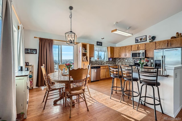 kitchen with light wood-style flooring, light countertops, appliances with stainless steel finishes, tasteful backsplash, and decorative light fixtures
