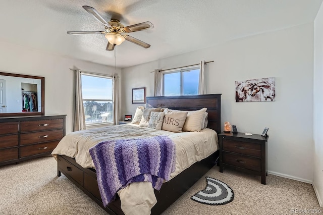 bedroom featuring light carpet, multiple windows, a textured ceiling, and baseboards