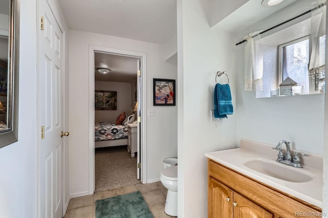 ensuite bathroom with toilet, connected bathroom, vanity, tile patterned flooring, and baseboards