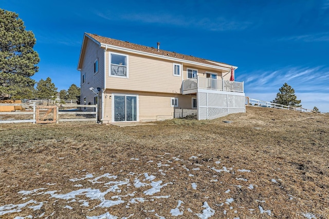 rear view of house featuring fence and a balcony