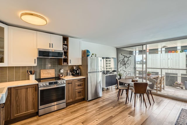 790 N Washington St Unit 1003, Denver, CO 80203 - kitchen with appliances with stainless steel finishes, light countertops, white cabinetry, light wood-style floors, and floor to ceiling windows
