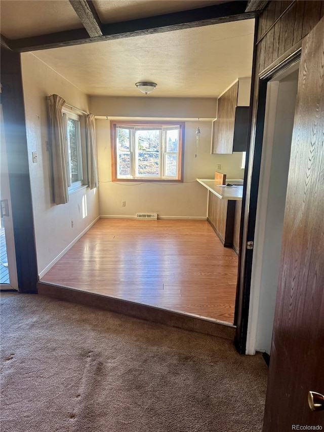 kitchen with beamed ceiling and light colored carpet