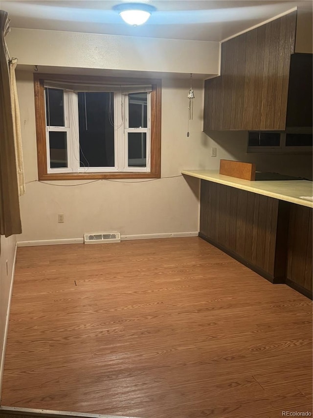 kitchen featuring pendant lighting, dark brown cabinets, and light hardwood / wood-style flooring