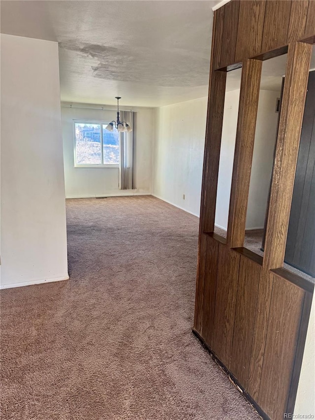 unfurnished room featuring carpet flooring, wooden walls, and a chandelier