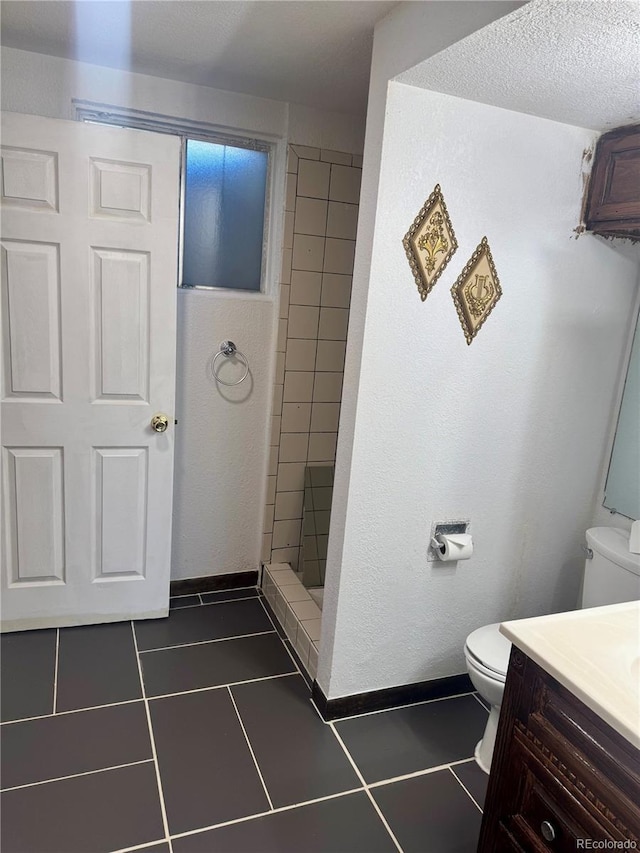 bathroom with a tile shower, tile patterned flooring, a textured ceiling, toilet, and vanity