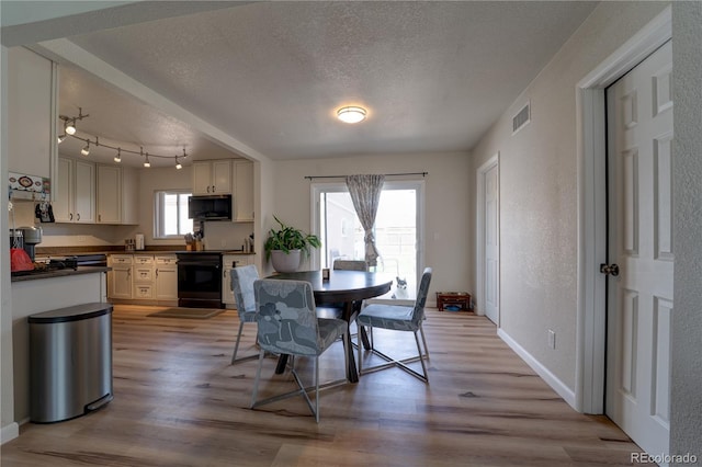 701 Tucson, Aurora, CO 80011 - dining room featuring a textured ceiling, light wood-style floors, and baseboards