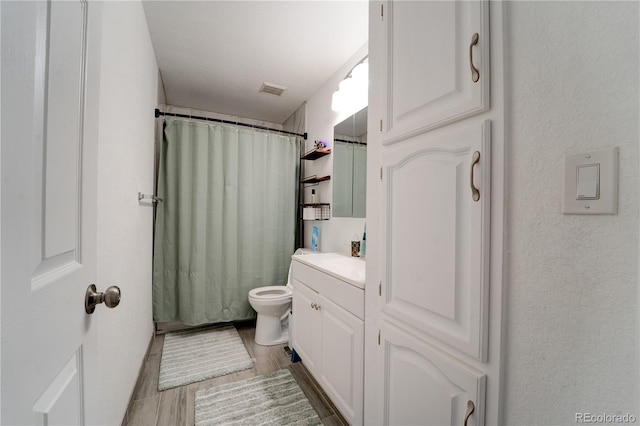 701 Tucson, Aurora, CO 80011 - bathroom featuring vanity, toilet, a shower with shower curtain, wood finished floors, and a textured wall