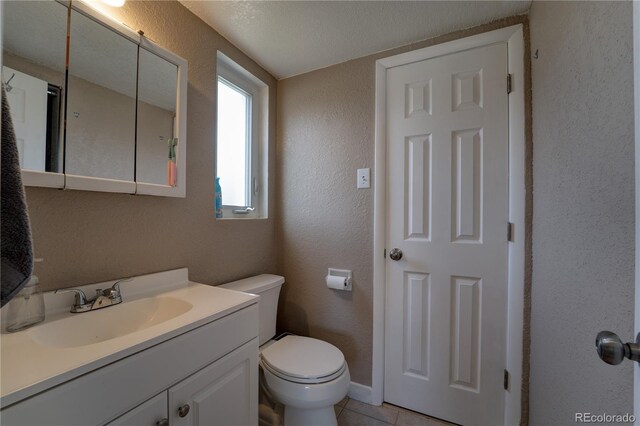 701 Tucson, Aurora, CO 80011 - bathroom with a textured wall, vanity, toilet, and tile patterned flooring