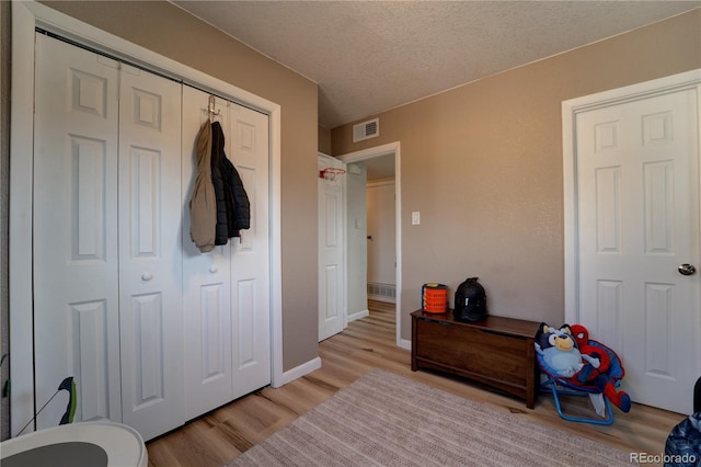701 Tucson, Aurora, CO 80011 - bedroom featuring light wood-style flooring, a closet, a textured ceiling, and baseboards