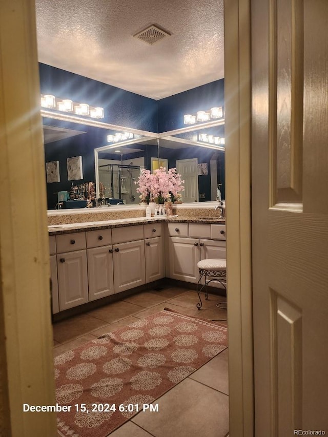 bathroom with tile patterned flooring, vanity, and a textured ceiling