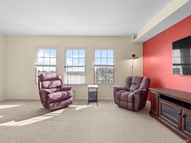 living area featuring baseboards, visible vents, and light carpet