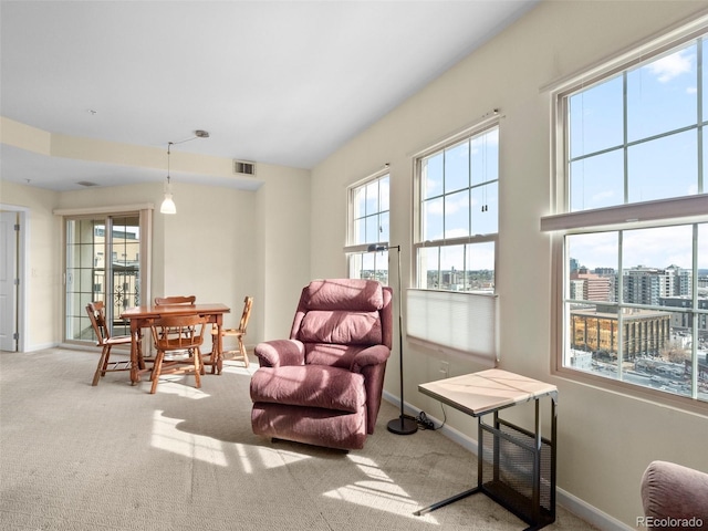 living area with a wealth of natural light, carpet flooring, baseboards, and visible vents