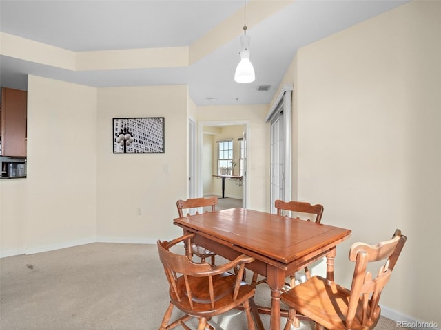 dining space featuring light carpet, visible vents, and baseboards