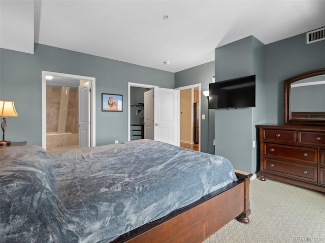 bedroom with visible vents, light colored carpet, and ensuite bath