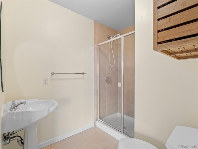 full bathroom with tile patterned floors, toilet, a sink, a shower stall, and baseboards