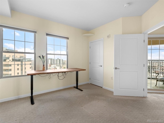 unfurnished office featuring carpet flooring, plenty of natural light, and baseboards