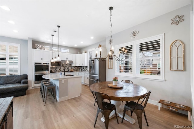 dining space featuring an inviting chandelier, recessed lighting, baseboards, and light wood-type flooring