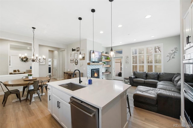 kitchen featuring stainless steel appliances, open floor plan, a glass covered fireplace, and a sink