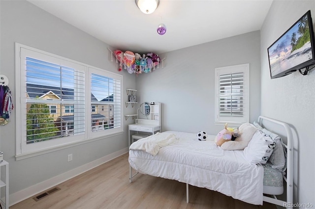 bedroom with visible vents, light wood finished floors, and baseboards