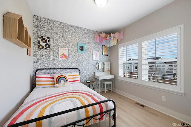 bedroom with baseboards, wood finished floors, and visible vents
