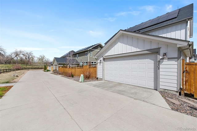 view of property exterior with board and batten siding, fence, driveway, and roof with shingles