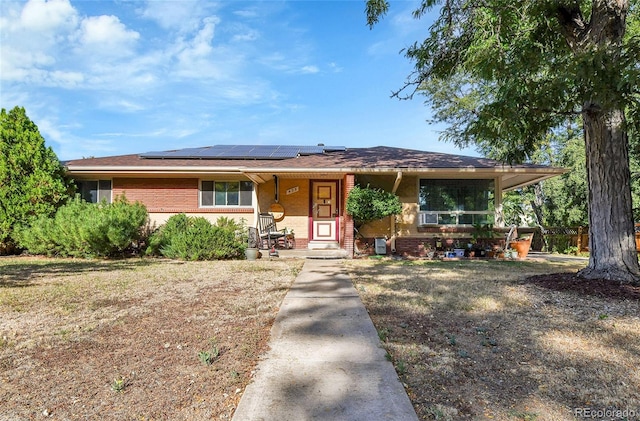 view of front of property featuring a front lawn, solar panels, and a porch