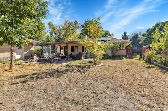 back of property with solar panels, a chimney, fence, a patio area, and brick siding