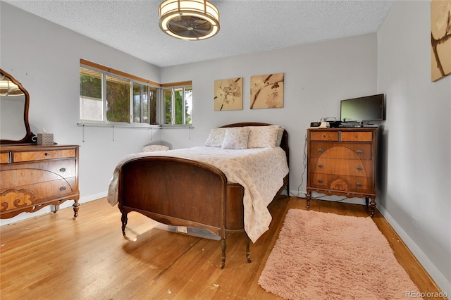 bedroom featuring a textured ceiling, baseboards, and wood finished floors