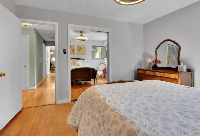 bedroom with a textured ceiling, a closet, baseboards, and light wood-style floors