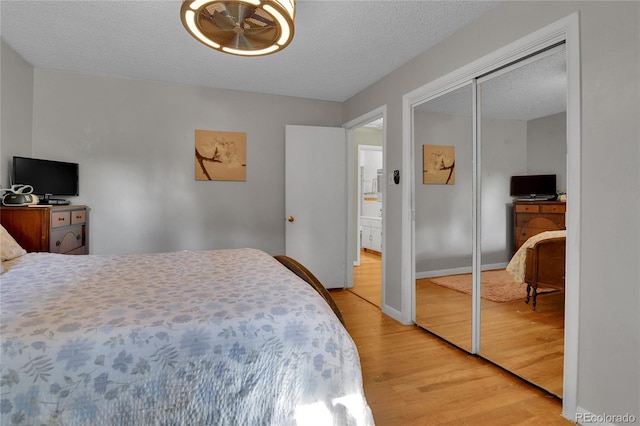 bedroom with a textured ceiling, light wood-style flooring, and baseboards