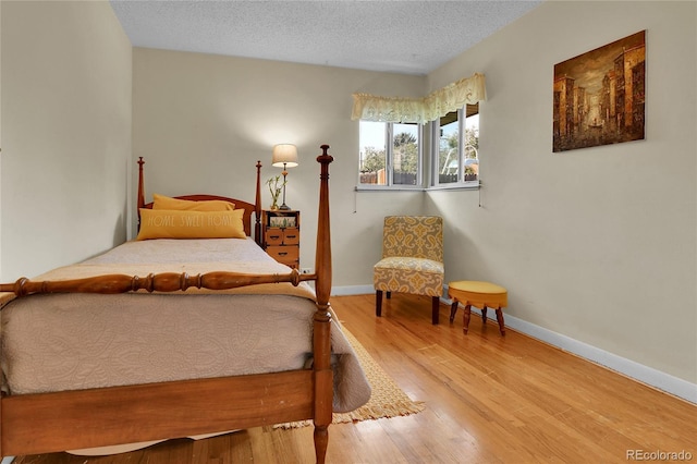 bedroom featuring a textured ceiling, baseboards, and wood finished floors