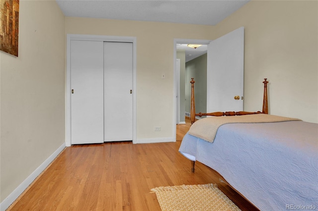 bedroom with light wood-type flooring, baseboards, and a closet