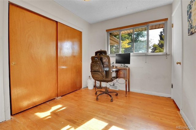 office featuring a textured ceiling, baseboards, and wood finished floors