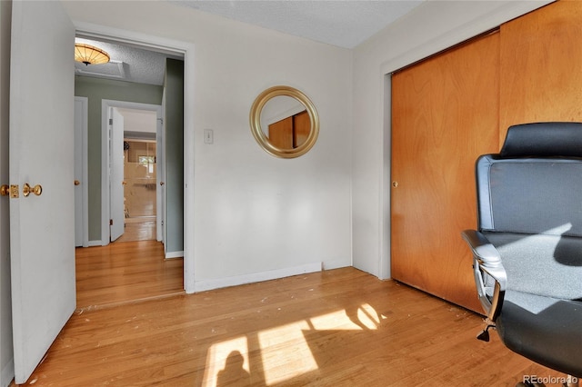 office area with a textured ceiling, wood finished floors, and baseboards