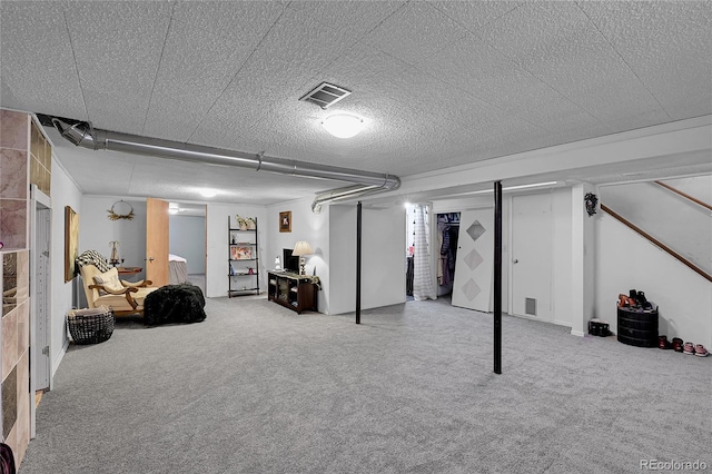 finished below grade area with visible vents, a textured ceiling, and carpet flooring