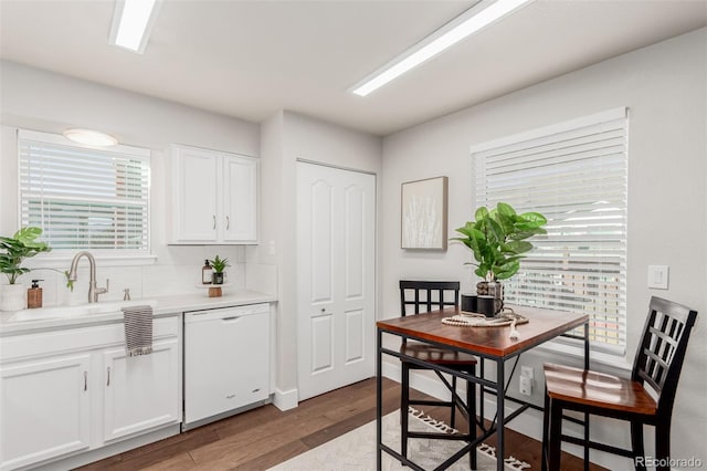 kitchen with backsplash, white dishwasher, sink, hardwood / wood-style flooring, and white cabinetry