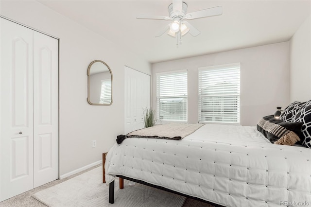 carpeted bedroom with ceiling fan and two closets