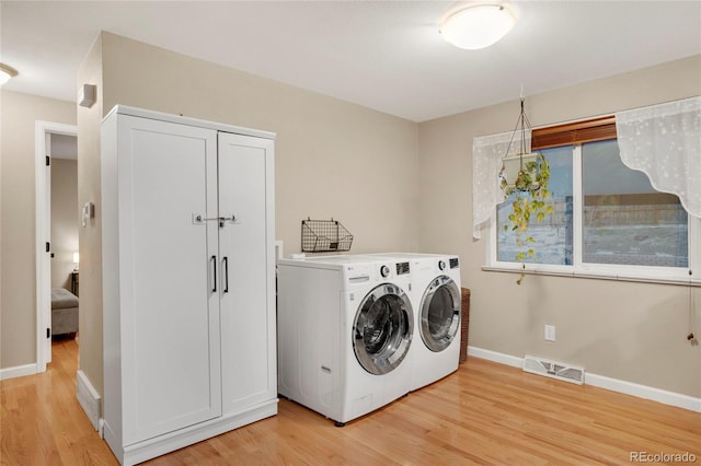 clothes washing area featuring visible vents, laundry area, washing machine and dryer, and light wood-style flooring