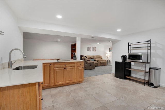 kitchen featuring light countertops, stainless steel microwave, a sink, and recessed lighting