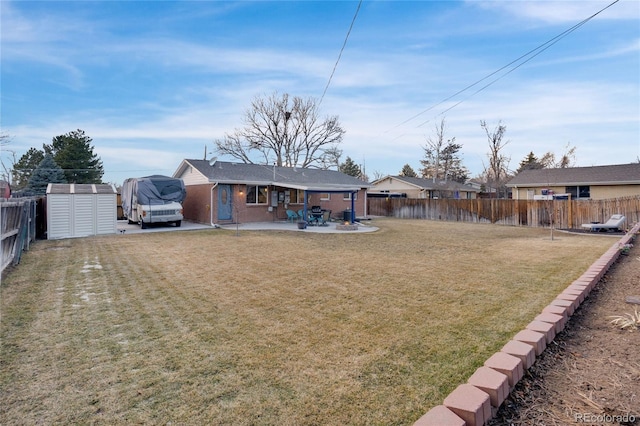 back of property featuring a patio, a fenced backyard, an outbuilding, a yard, and a shed