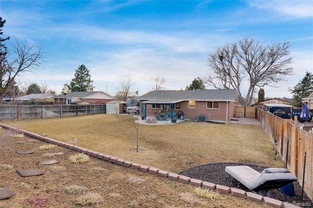 rear view of house with brick siding, a patio, central air condition unit, a lawn, and a fenced backyard